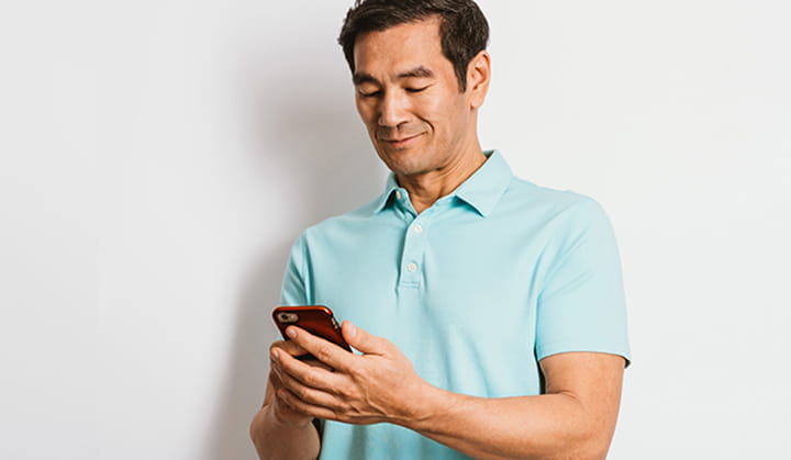 Persona con camiseta polo con el teléfono móvil enviando dinero con Zelle® y BOK.