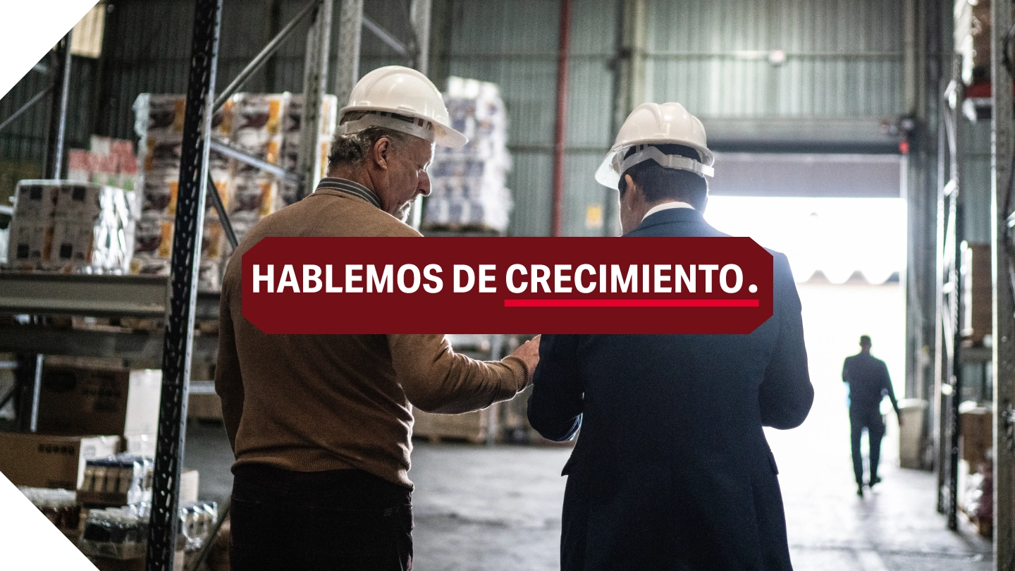 HABLEMOS DE CRECIMIENTO. Dos hombres con cascos caminando por un almacén.